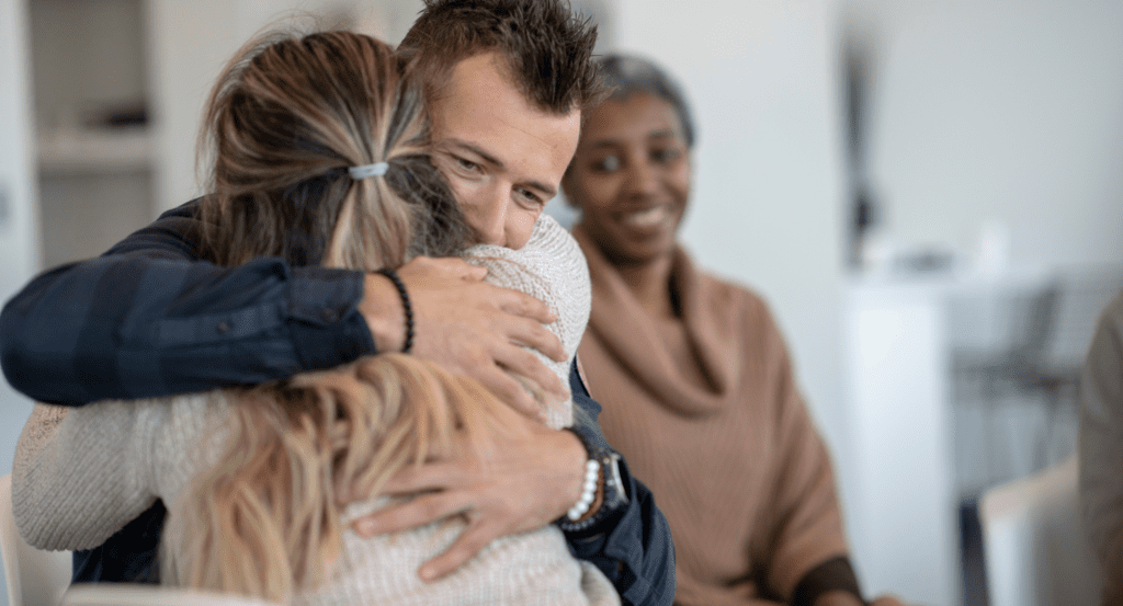 A man and woman embrace with happiness after recovering